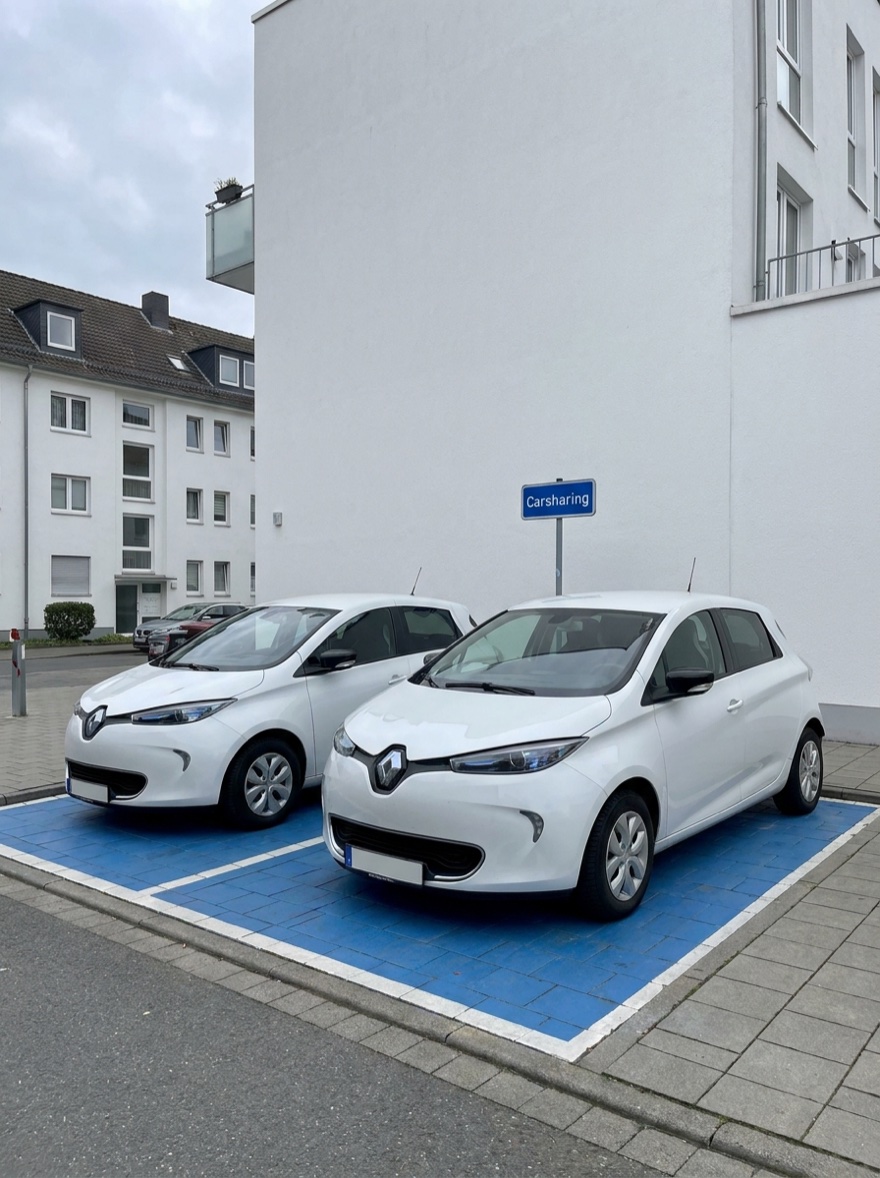 Two compact shared cars parked in their marked car-sharing spaces at the building