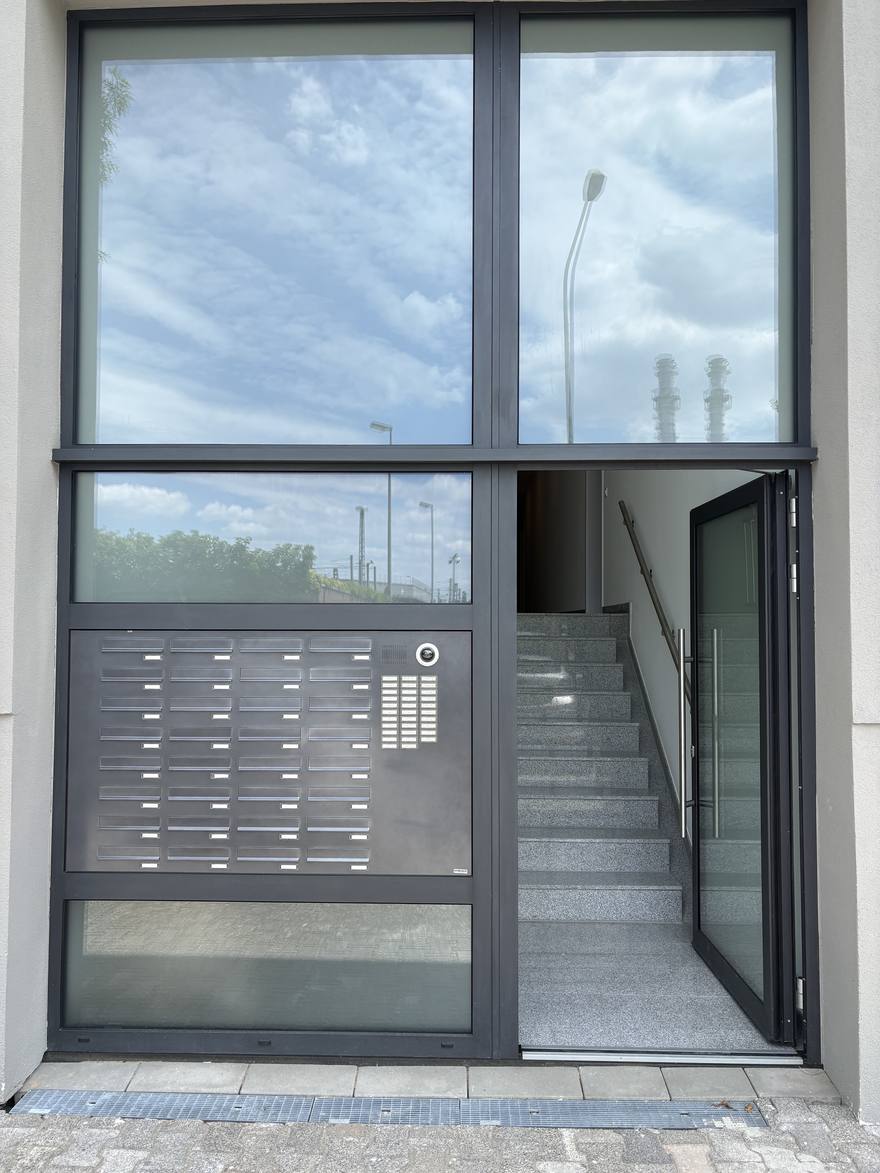 The glazed entrance on Heilbronner Straße, with the mailbox wall and video intercom