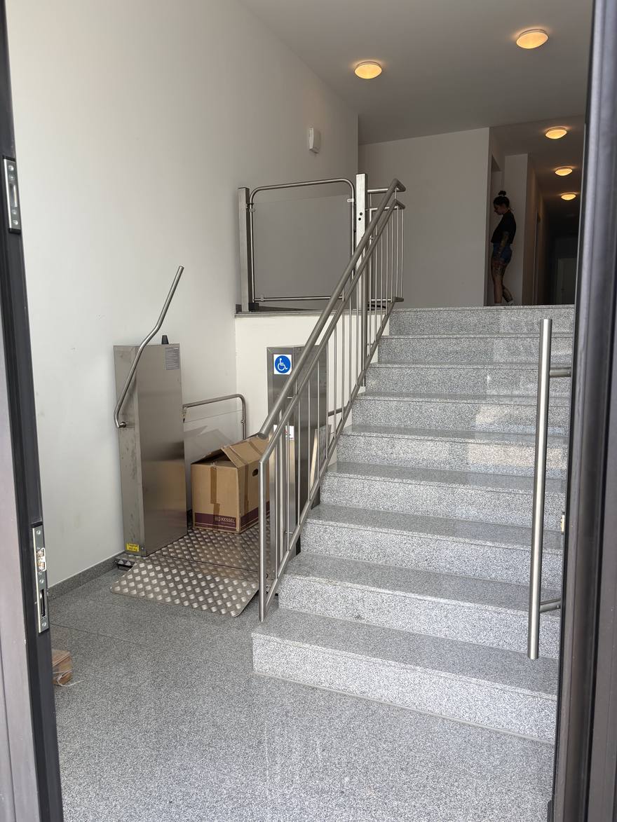 The stairwell inside the entrance, with a wheelchair platform lift beside the steps